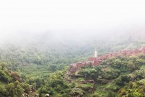 Туманний краєвид на село на схилі пагорбів — стокове фото