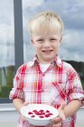 Retrato de menino no pátio com tigela de framboesas — Fotografia de Stock