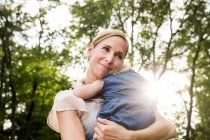 Mitte erwachsene Frau trägt Kleinkind-Tochter in sonnigem Park — Stockfoto