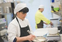 Panaderos masculinos y femeninos que trabajan en cocina comercial - foto de stock