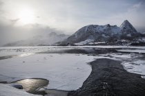 Вид на замерзлий берег і гору з низькими хмарами — стокове фото