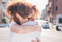 Young male hipster twins with red hair and beards hugging on city street — Stock Photo