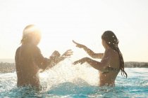 Couple s'amusant, éclaboussant dans la piscine extérieure — Photo de stock