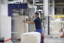 Trabalhador usando a máquina na fábrica de embalagens de papel — Fotografia de Stock