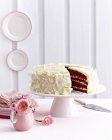 Red velvet layer cake covered in icing on cakestand — Stock Photo
