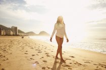 Mature woman strolling on sunlit Copacabana beach, Rio De Janeiro, Brazil — Stock Photo