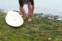 Surfista amarrando trela de prancha no tornozelo — Fotografia de Stock