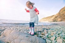 Chica caminando sobre guijarros, Millook Beach, Cornwall - foto de stock