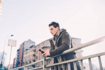 Mann lehnt mit Smartphone an Geländer — Stockfoto