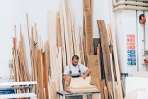 Carpinteiro selecionando madeira na oficina — Fotografia de Stock