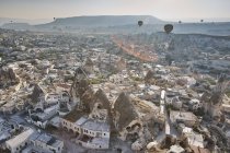 Elevated view of hot air balloons over rock formations and dwellings, Cappadocia, Anatolia,Turkey — Stock Photo