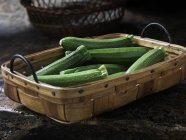 Fresh organic baby long courgettes in basket — Stock Photo