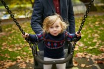 Pai empurrando filha no playground swing — Fotografia de Stock