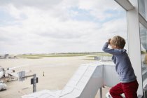 Boy looking out of airport window at runway, Londres, Reino Unido — Fotografia de Stock