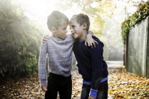 Retrato de gemelos, al aire libre, cara a cara, rodeado de hojas de otoño - foto de stock