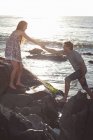 Casal escalando pedras na praia — Fotografia de Stock