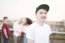 Ragazzo adolescente che indossa il berretto da baseball, persone in background — Foto stock