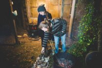 Пара с помощью щипцов, чтобы удалить глиняные горшки из огня, улыбаясь — стоковое фото