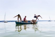 Grupo de amigos buceando desde el barco en el lago, Schondorf, Ammersee, Bavaria, Alemania - foto de stock