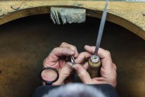 Hands of jewellery craftsman using file tool on platinum ring — Stock Photo