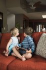 Geschwister drehen sich vom digitalen Tablet auf dem heimischen Sofa um — Stockfoto