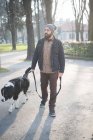 Hombre adulto medio paseando perro a través del parque - foto de stock