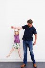 Portrait d'homme mature avec sa fille suspendue à son bras devant un mur blanc — Photo de stock