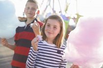 Irmão e irmã comendo fio dental rosa no parque de diversões — Fotografia de Stock