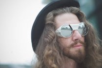 Primo piano di giovane hippy maschile con capelli lunghi e occhiali da sole — Foto stock