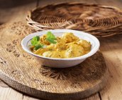 Hühnchen-Korma-Curry in einer Schüssel garniert mit Koriander auf Holzbrett — Stockfoto