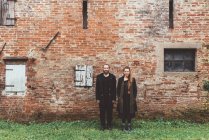 Retrato de casal na frente do edifício velho da fazenda da parede de tijolo — Fotografia de Stock