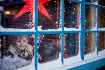 Dos hermanos mirando por la ventana de la cabina en Navidad - foto de stock