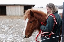Mulher sorrindo com cavalo na jarda — Fotografia de Stock