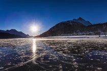 Paisaje con lago congelado y montañas a la luz del sol - foto de stock