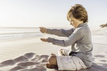 Garçon jouer avec sable sur la plage — Photo de stock