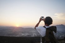 Rückansicht junger Mann fotografiert Landschaft und Sonnenuntergang auf Smartphone, Java, Spanien — Stockfoto