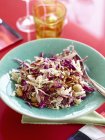 Red and white cabbage salad with macadamia nuts in blue bowl — Stock Photo
