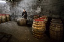Trabalhador rolando barril de uísque em armazém de destilaria de uísque — Fotografia de Stock