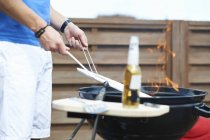 Cropped shot of mid adult man barbecuing at rooftop barbecue — Stock Photo