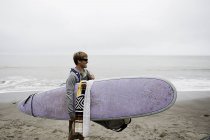 Joven surfista masculino en la playa brumosa, Bolinas, California, EE.UU. - foto de stock