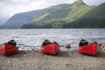 Tre canoe rosse ormeggiate sulla riva lago distretto parco nazionale, Inghilterra — Foto stock