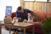 Mittlerer erwachsener Mann streichelt Hund im Bilderrahmen-Showroom — Stockfoto