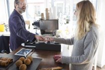 Cliente feminino entrega pagamento de notas ao proprietário do café — Fotografia de Stock