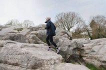 Metà corridore femminile adulto che corre su formazione rocciosa — Foto stock