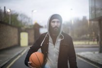 Portrait of mid adult man in street, holding basketball — Stock Photo