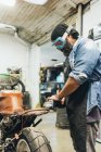 Homme mûr, travaillant sur la moto dans le garage — Photo de stock