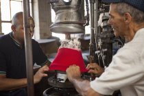 Шляпники растягивая ткань на плесени в мастерской — стоковое фото
