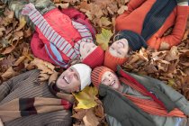 Família deitada juntas em folhas de outono, rindo — Fotografia de Stock