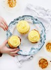 Imagen recortada de niño recogiendo cupcakes de plato - foto de stock