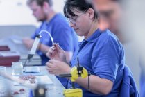 Female worker assembling electromagnets on production line in electronics factory — Stock Photo